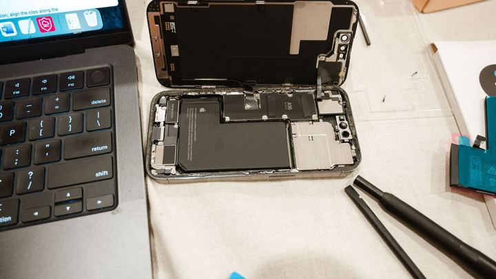 An opened smartphone showing its battery during a repair